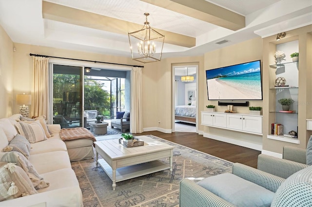 living room featuring dark hardwood / wood-style floors, ceiling fan with notable chandelier, and a tray ceiling