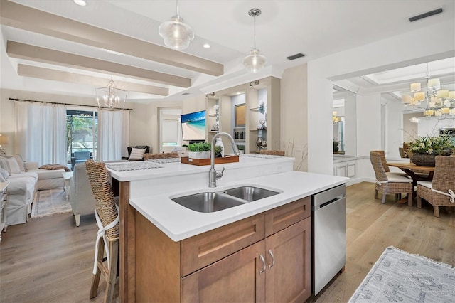 kitchen with a kitchen island with sink, sink, pendant lighting, a notable chandelier, and dishwasher