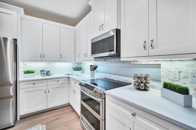 kitchen with light wood-type flooring, white cabinetry, stainless steel appliances, and tasteful backsplash