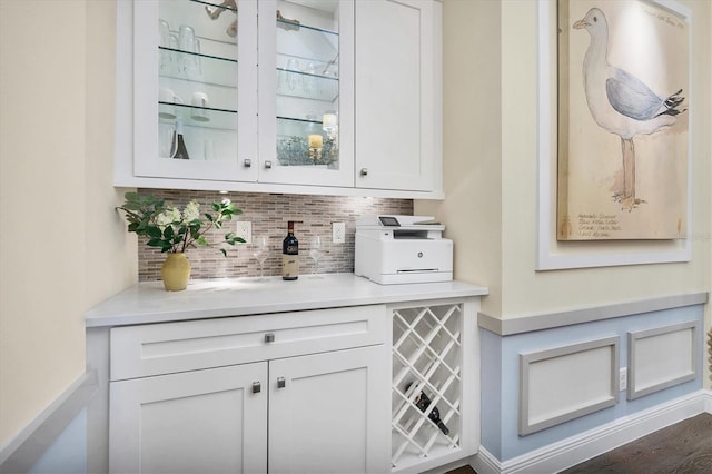 bar featuring backsplash, white cabinetry, and dark wood-type flooring