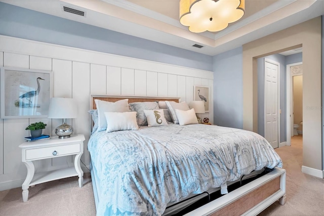 carpeted bedroom with a raised ceiling and a closet