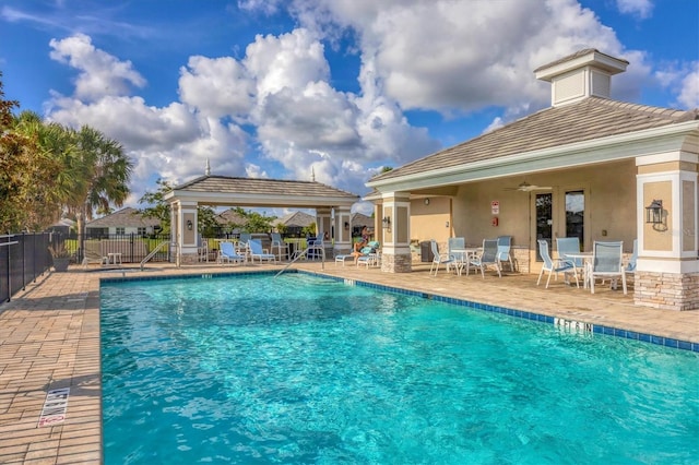 view of swimming pool with ceiling fan and a patio area