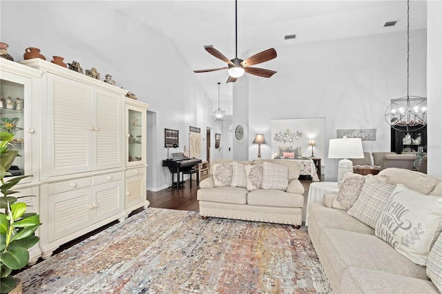 living room with high vaulted ceiling, dark wood-type flooring, and ceiling fan with notable chandelier