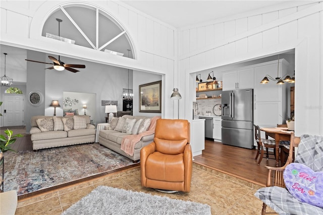 living room with a towering ceiling, ceiling fan with notable chandelier, hardwood / wood-style floors, and sink