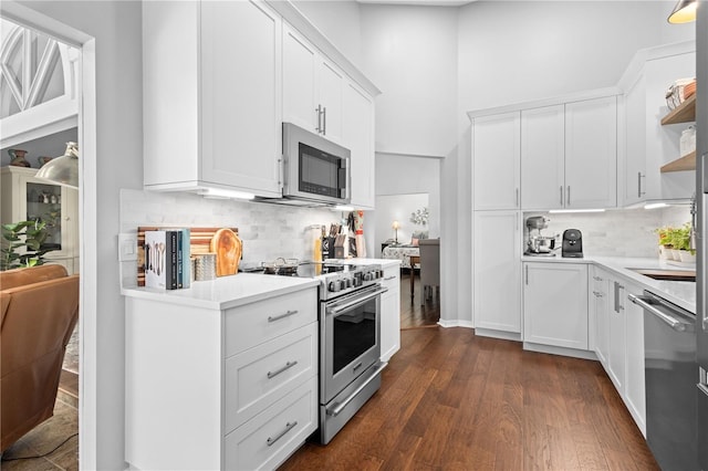 kitchen with dark hardwood / wood-style flooring, white cabinetry, tasteful backsplash, and stainless steel appliances