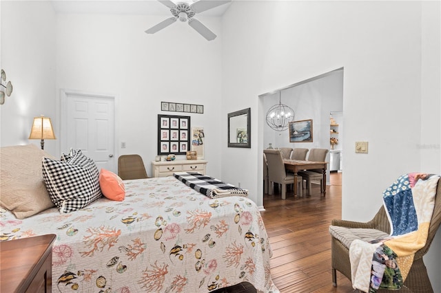 bedroom with a towering ceiling, ceiling fan with notable chandelier, and dark hardwood / wood-style flooring