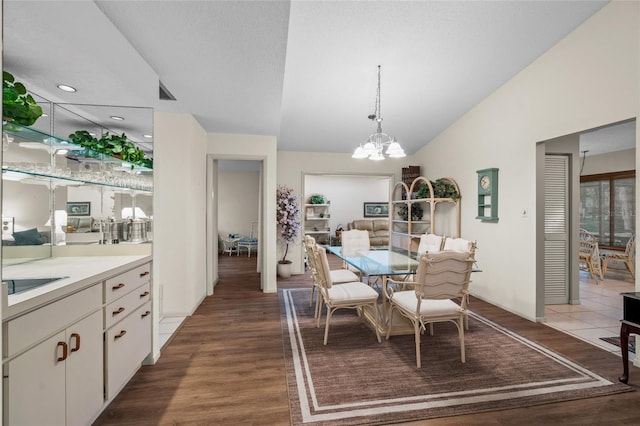 dining area featuring an inviting chandelier, vaulted ceiling, and hardwood / wood-style floors