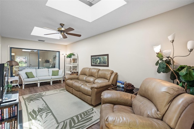 living room featuring ceiling fan, a skylight, and dark wood-type flooring