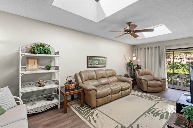 living room with a textured ceiling, ceiling fan, hardwood / wood-style flooring, and a skylight