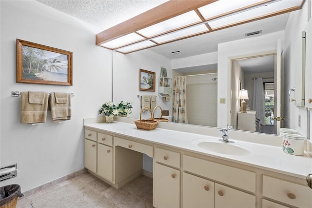 bathroom with tile flooring, a textured ceiling, and oversized vanity