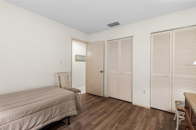 bedroom featuring two closets and dark wood-type flooring