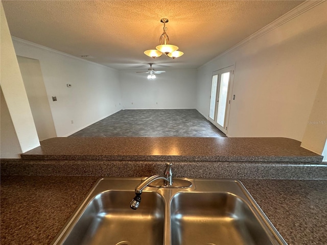 kitchen with decorative light fixtures, ceiling fan, tile flooring, sink, and a textured ceiling