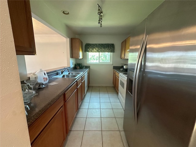 kitchen with electric range, stainless steel refrigerator with ice dispenser, rail lighting, sink, and light tile flooring