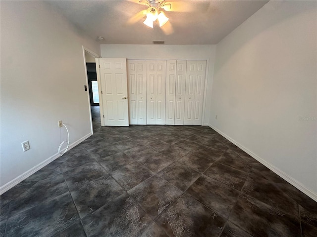 unfurnished bedroom featuring ceiling fan, a closet, and dark tile floors