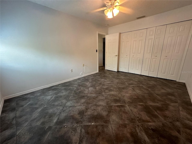 unfurnished bedroom featuring a closet, ceiling fan, and dark tile floors