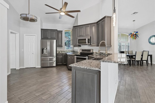 kitchen with a healthy amount of sunlight, light stone counters, sink, and appliances with stainless steel finishes