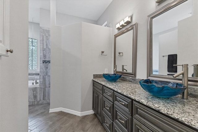 bathroom with a tile shower, vanity, and wood-type flooring