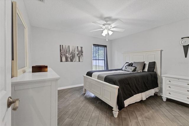 bedroom with a textured ceiling, ceiling fan, and dark wood-type flooring