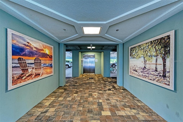 corridor with a textured ceiling and elevator