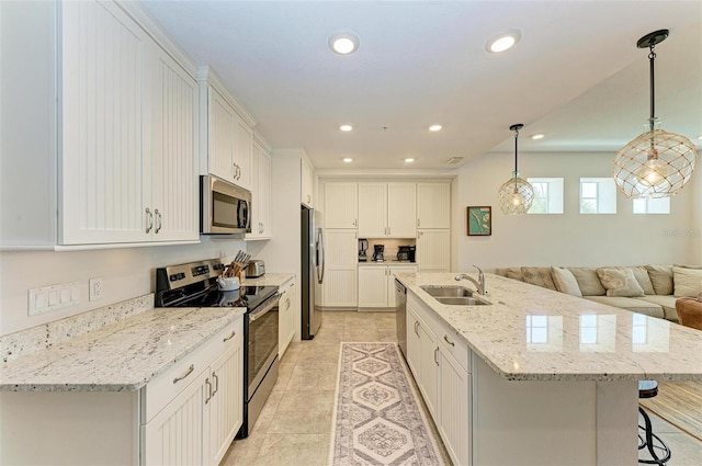 kitchen with an island with sink, stainless steel appliances, light tile floors, sink, and a kitchen bar