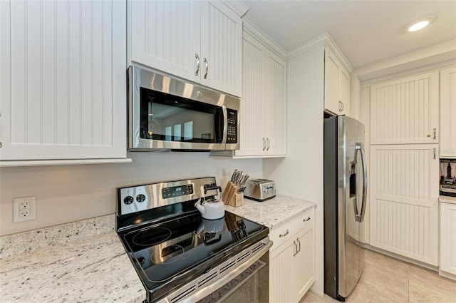 kitchen with white cabinetry, appliances with stainless steel finishes, light stone countertops, and light tile flooring