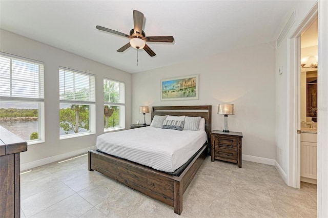 tiled bedroom featuring ceiling fan and ensuite bath