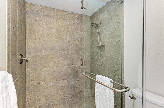 bathroom featuring a shower with door and toilet