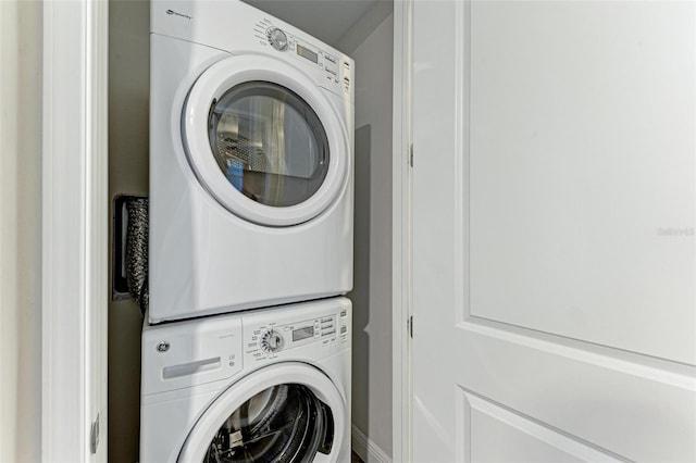 clothes washing area with stacked washing maching and dryer