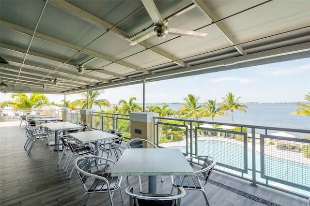 deck with ceiling fan, a water view, and a fenced in pool