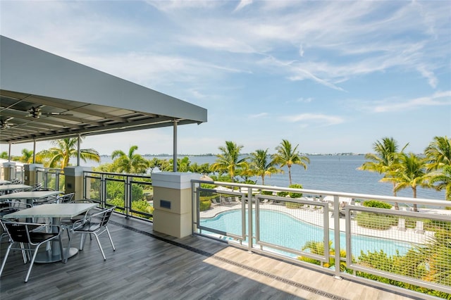 deck featuring ceiling fan, a water view, and a fenced in pool