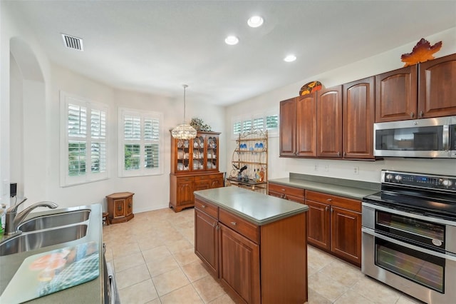 kitchen with stainless steel appliances, a center island, light tile flooring, and decorative light fixtures