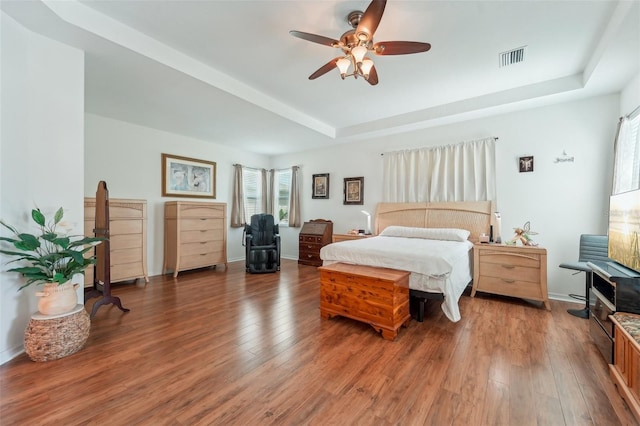 bedroom featuring ceiling fan, a tray ceiling, and hardwood / wood-style floors