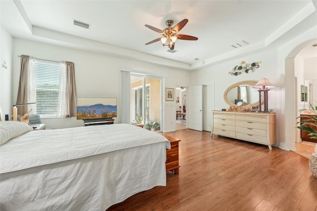 bedroom featuring ceiling fan, a tray ceiling, and hardwood / wood-style flooring