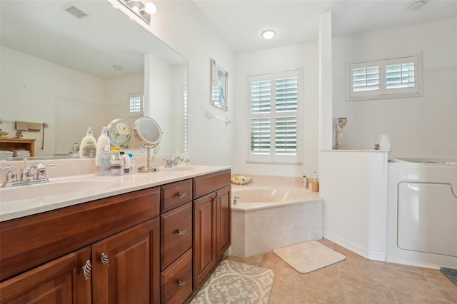 bathroom featuring a bath to relax in, tile flooring, washer / clothes dryer, and dual bowl vanity