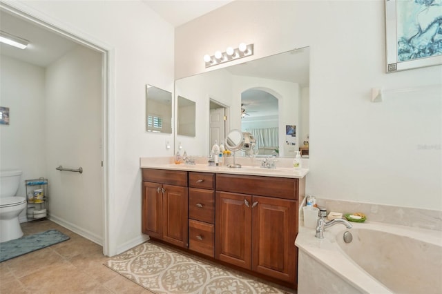 bathroom with a tub, dual vanity, toilet, and tile floors