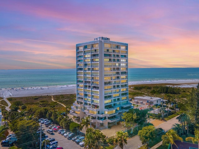 outdoor building at dusk featuring a view of the beach and a water view