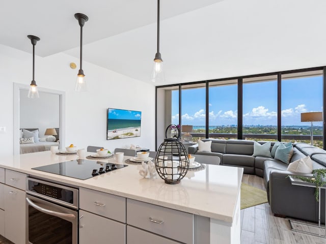 kitchen with black electric cooktop, decorative light fixtures, a wealth of natural light, and stainless steel oven