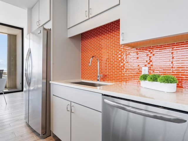 kitchen featuring white cabinets, sink, light hardwood / wood-style flooring, appliances with stainless steel finishes, and tasteful backsplash