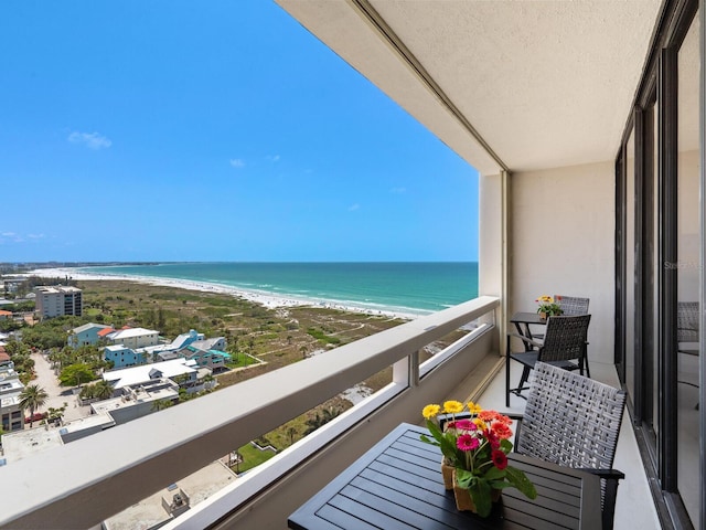 balcony featuring a view of the beach and a water view