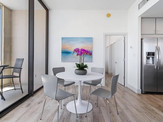 dining area featuring light hardwood / wood-style floors and a wall of windows