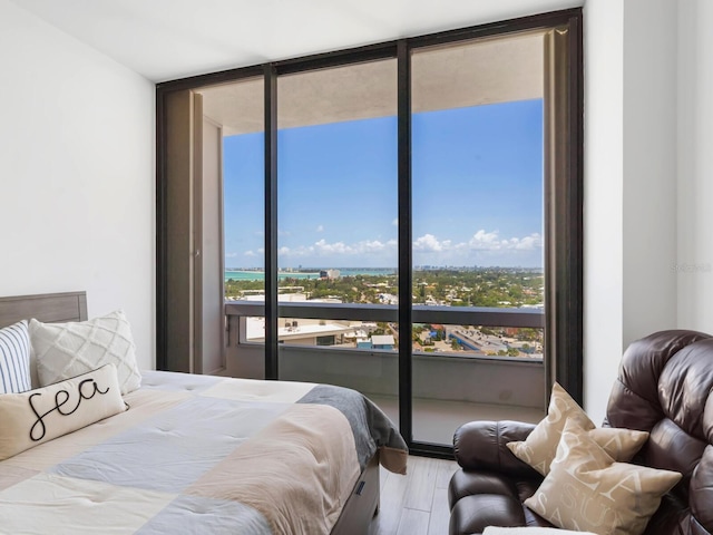 bedroom with access to exterior, hardwood / wood-style floors, and a wall of windows