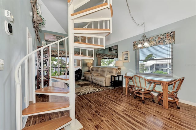 stairway featuring high vaulted ceiling, wood-type flooring, and a chandelier