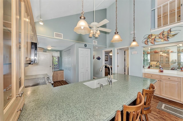 kitchen featuring light brown cabinets, ceiling fan, hardwood / wood-style flooring, high vaulted ceiling, and sink