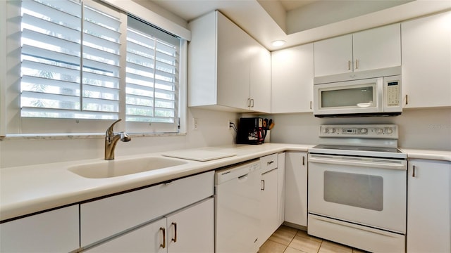 kitchen with white cabinets, light tile patterned floors, white appliances, and sink