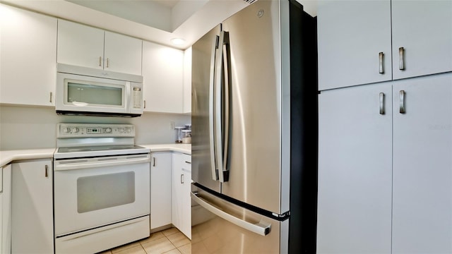 kitchen with white cabinets, light tile patterned flooring, and white appliances