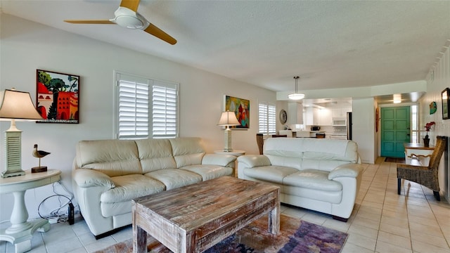 living room with ceiling fan, light tile patterned flooring, and a textured ceiling