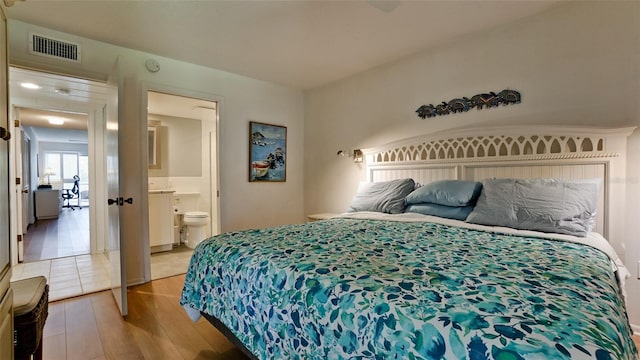 bedroom featuring ensuite bathroom and light hardwood / wood-style flooring