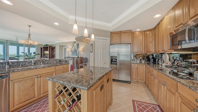 kitchen featuring stainless steel appliances, a center island, hanging light fixtures, a chandelier, and a tray ceiling