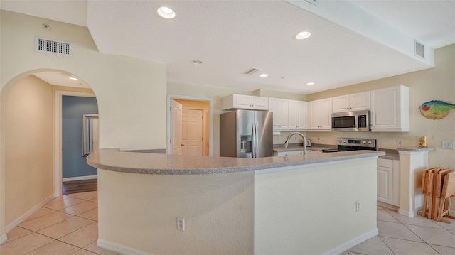 kitchen with stainless steel appliances, sink, white cabinetry, and light tile floors