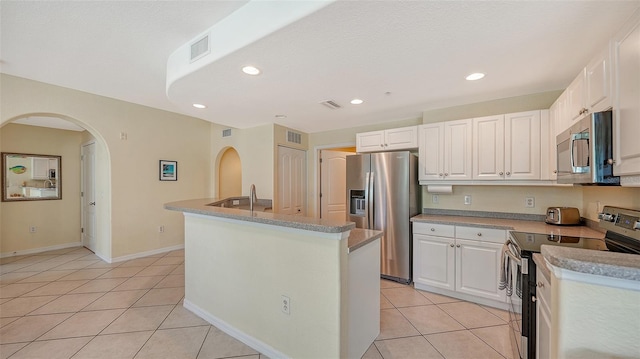 kitchen featuring a kitchen island with sink, white cabinets, light tile flooring, and stainless steel appliances